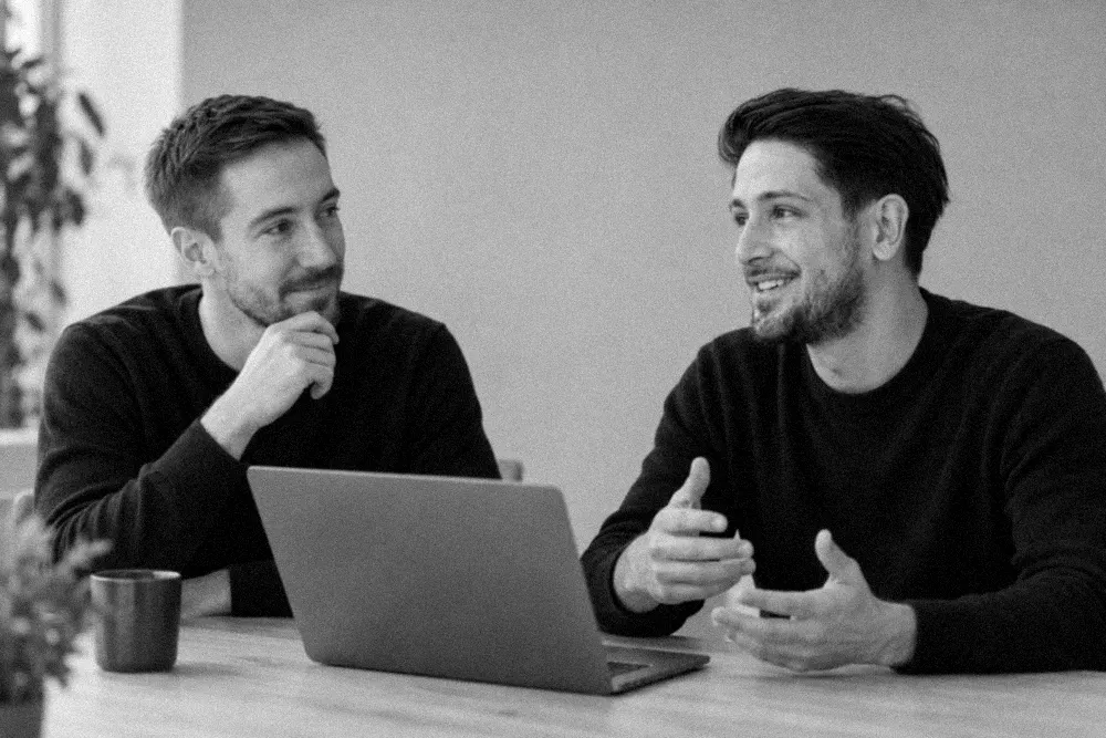 Hippolyte et Karim, les deux associés de Flash Ads, en discussion autour d'un ordinateur portable